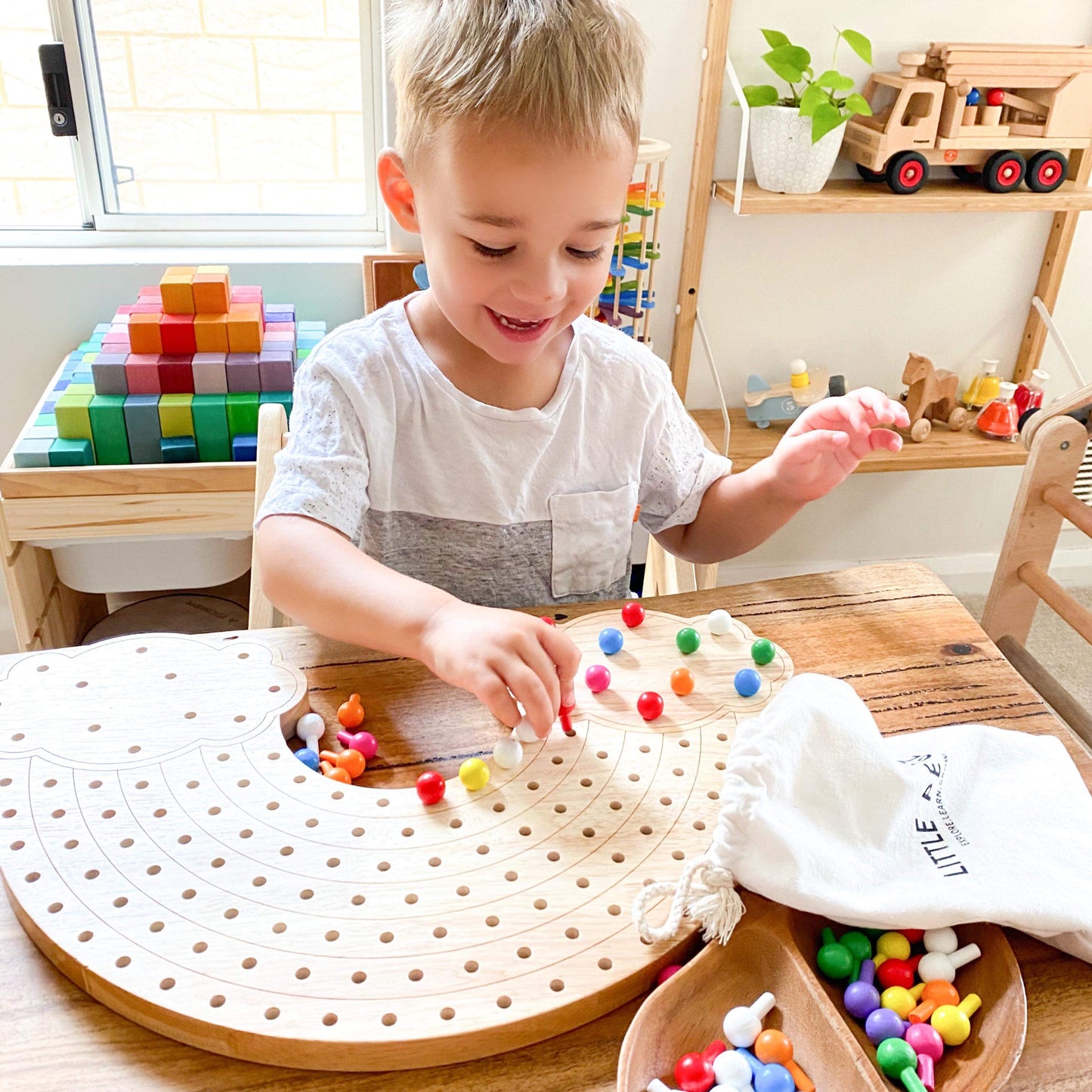 Boy  playing with natural wooden pegboard. Toddler playing with educational toy. Boy playing in daycare centre. Natural Wooden Rainbow Pegboards. Wooden Educational & Sensory Play Toy. Wooden Pegs, Wooden Peg Board. Australian Owned Company - Little Pegz